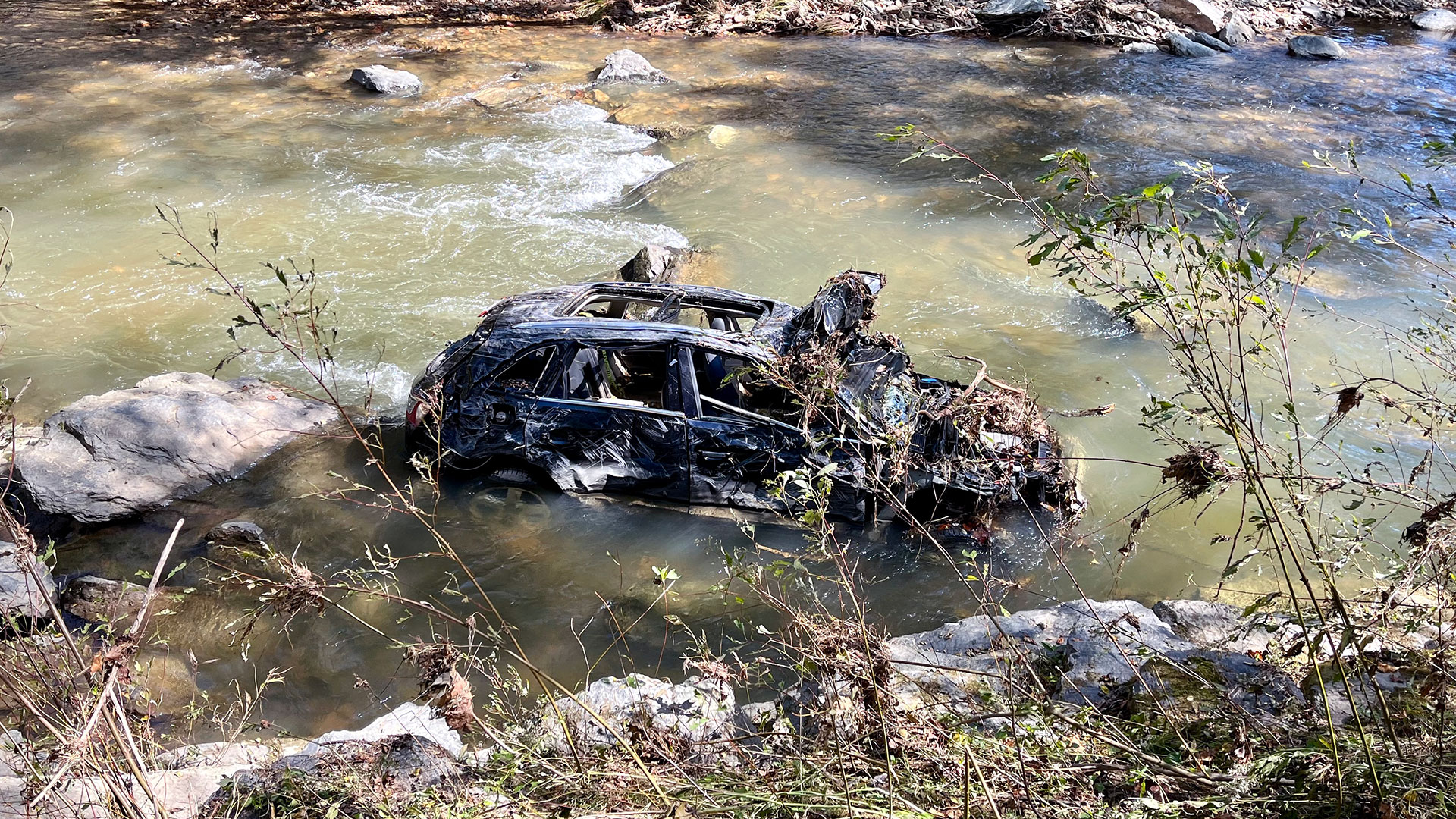 A battered SUV runs aground as the waters of the Watauga River subside.