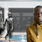 A South Sudanese refugee wearing a yellow hoodie smiles at the camera while standing in front of the Carter Presidential Center entrance. Behind him are two bronze statues depicting African figures, and a small fountain is visible in the background. The Center’s name is prominently displayed in large letters above the entrance.