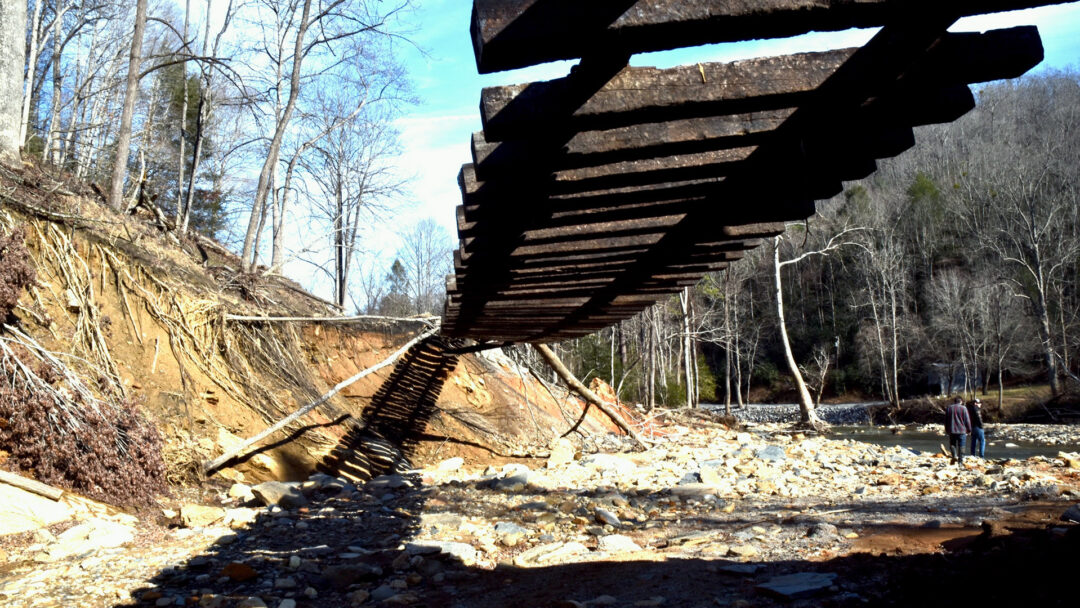 A photo of the aftermath of Hurricane Helene in Old Fort, NC shows railroad tracks suspended in midair. McDowell County flood relief efforts continue as the community rebounds from devastation.