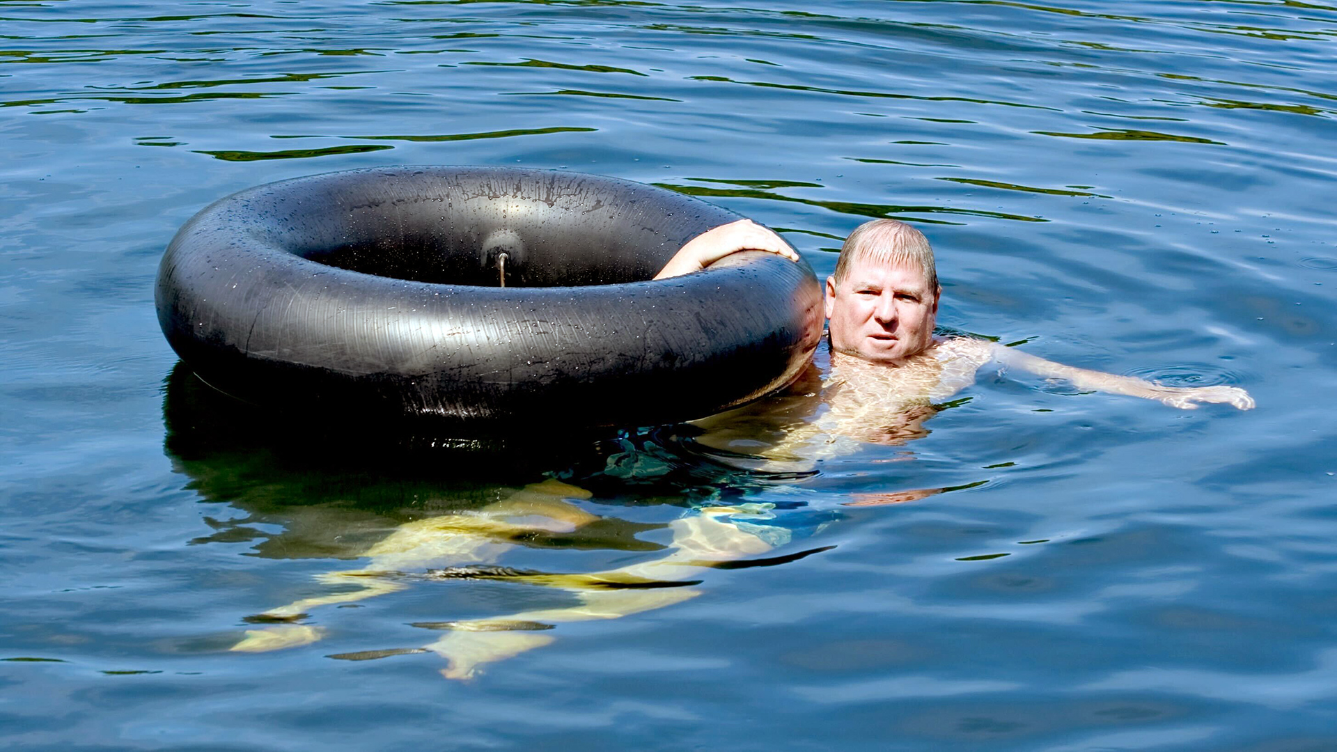 A man tubing on a river, evoking themes from Beth Copeland's 'Tubing on the New River,' a poem by the award-winning North Carolina poet about aging and companionship.