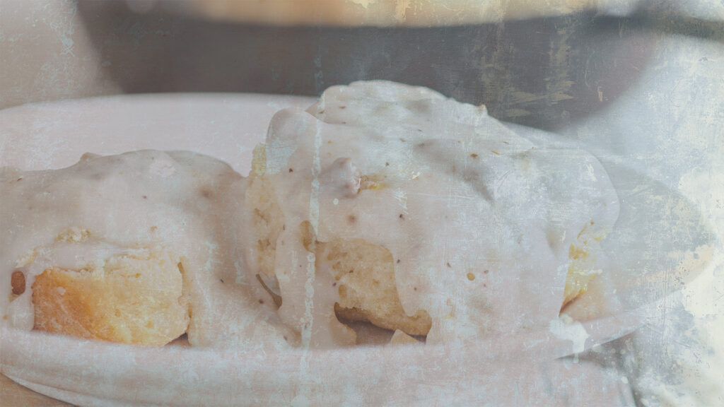 Close-up of biscuits covered in creamy gravy on a white plate, symbolizing Appalachian traditions in Hilda Downer's poetry about resilience and heritage. Includes themes from Appalachian poetry by Hilda Downer, Aunt Honeybee's Bread Board analysis, and her Appalachian roots.