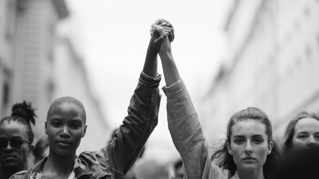 Protesters holding hands symbolize unity during Black History Month reflections, allyship, and the fight for racial justice.