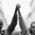 Protesters holding hands symbolize unity during Black History Month reflections, allyship, and the fight for racial justice.